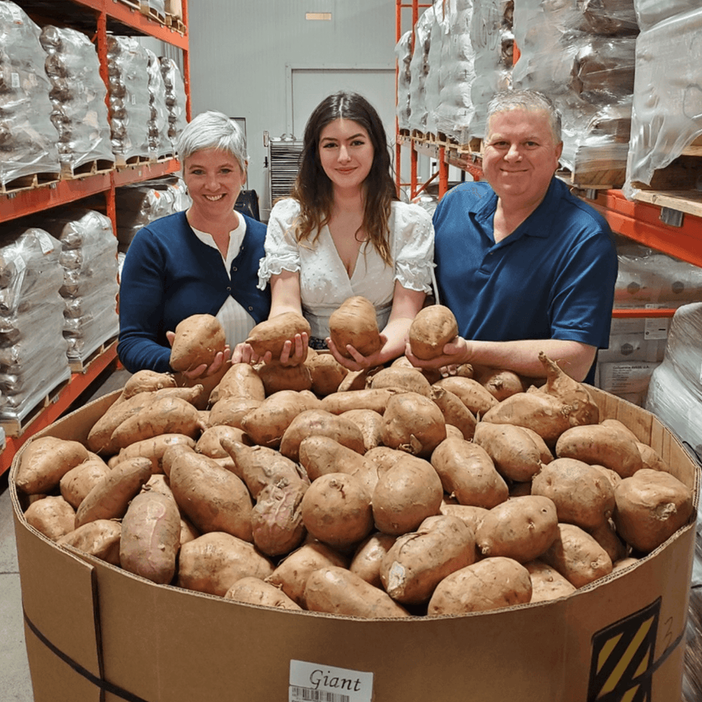 Margot and Joe and their daughter Lily, in front of a typical tote of sweet potatoes | Crumps' Naturals